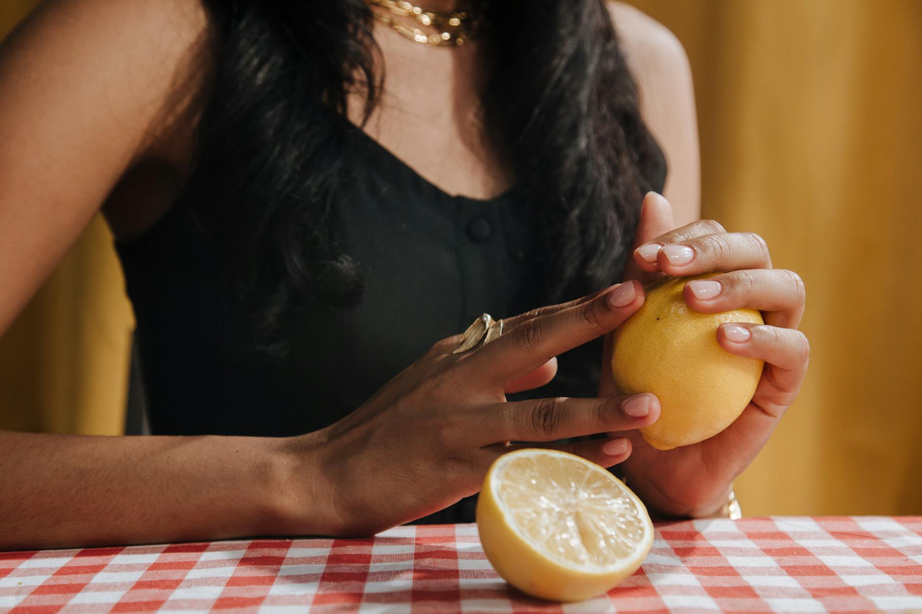 Close-up of a hand holding an orange vibrator against a minimalistic purple backdrop