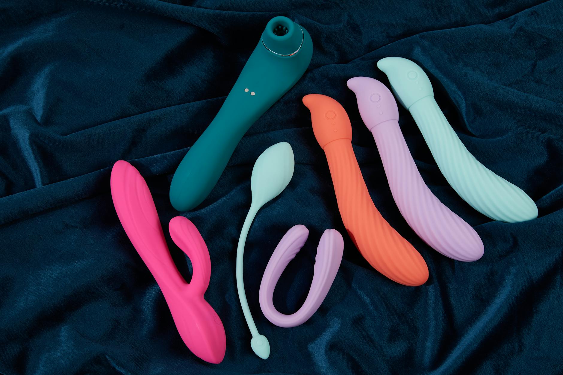 A hand holding a blue silicone vibrator against a purple background, symbolizing self-love and sensual wellness after treatment.