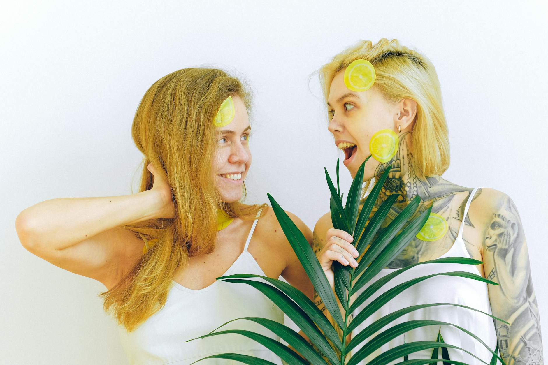 Two smiling women holding lemon slices indoors, representing joy and open communication about intimacy