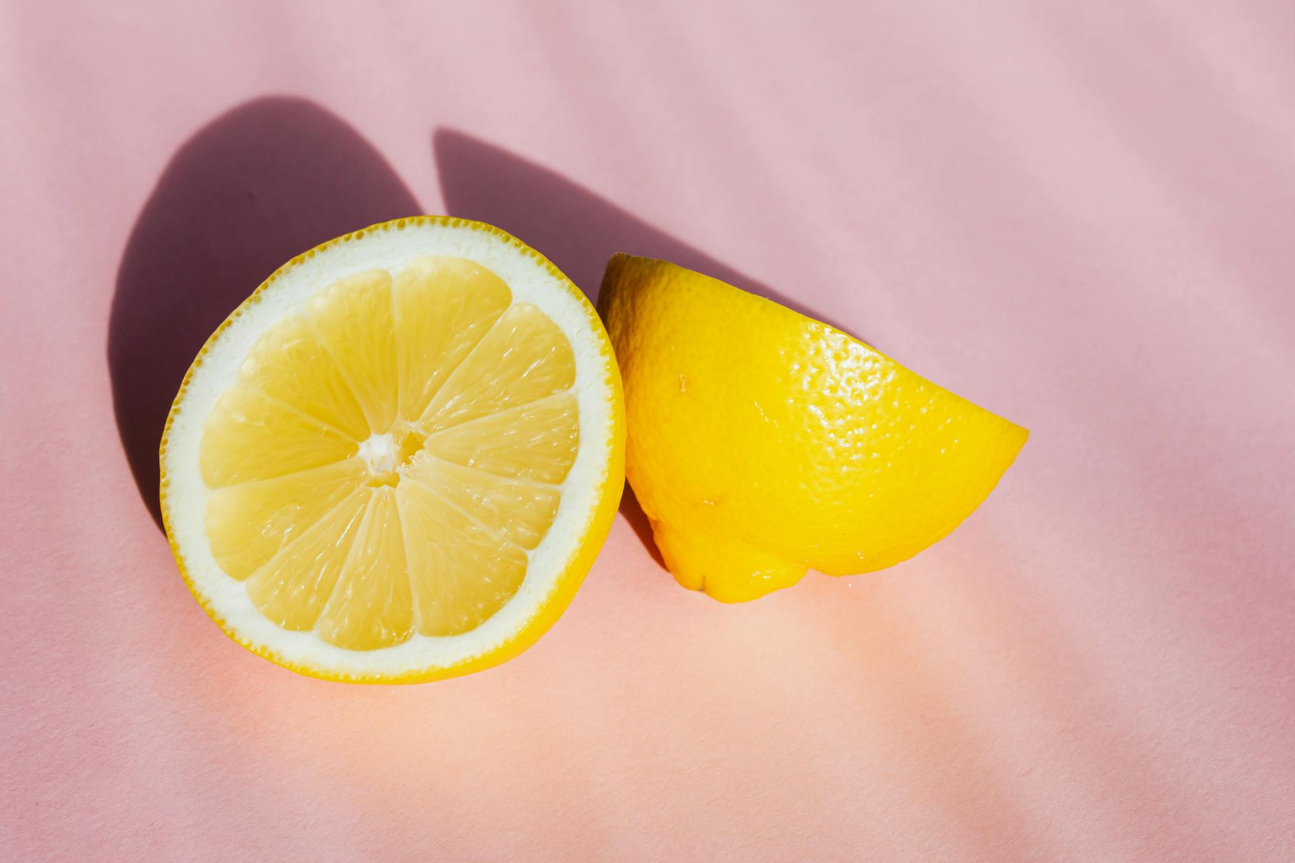 Limones frescos dispuestos sobre un fondo rosa brillante en luz natural
