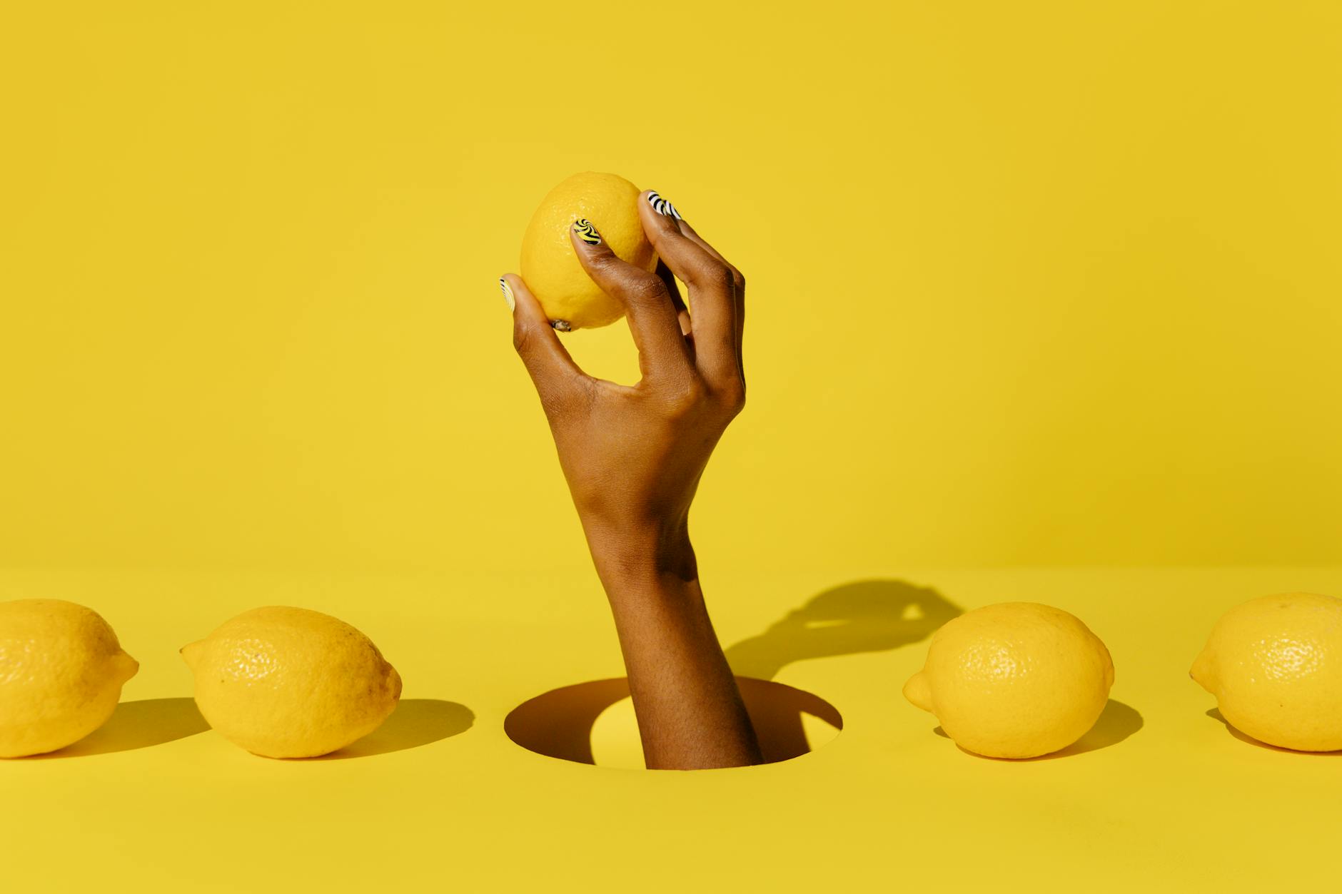 A hand holding a lemon against a vivid yellow background, symbolizing freshness and reconnection