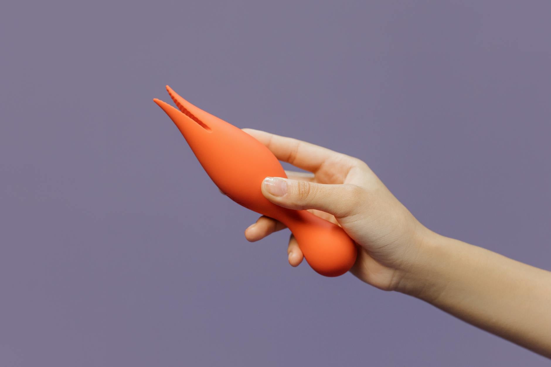 Close-up of a hand holding a vibrator, representing reclaiming sensation and pleasure during postpartum recovery