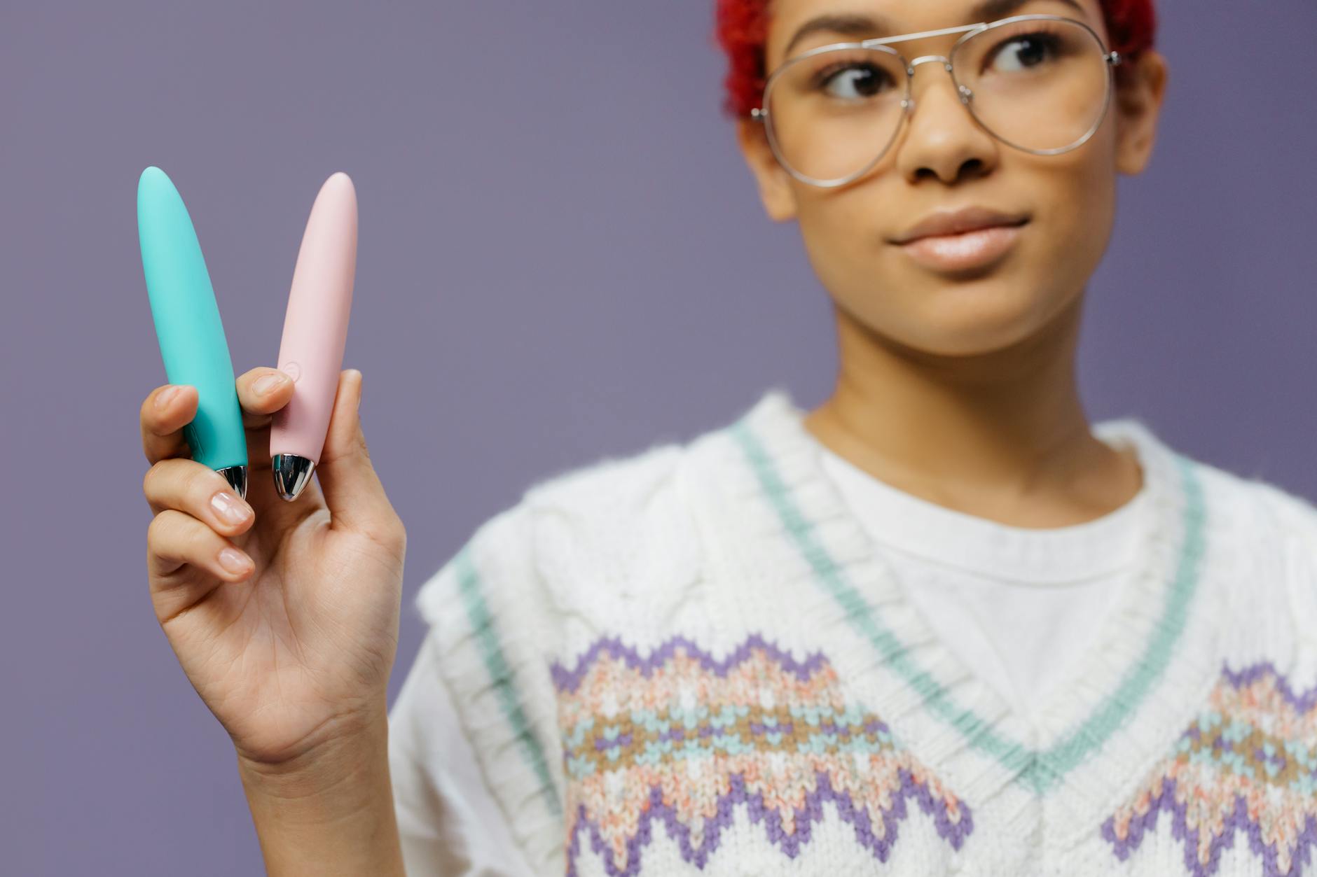 Intimate close-up of hands holding a sleek vibrator with a partner nearby