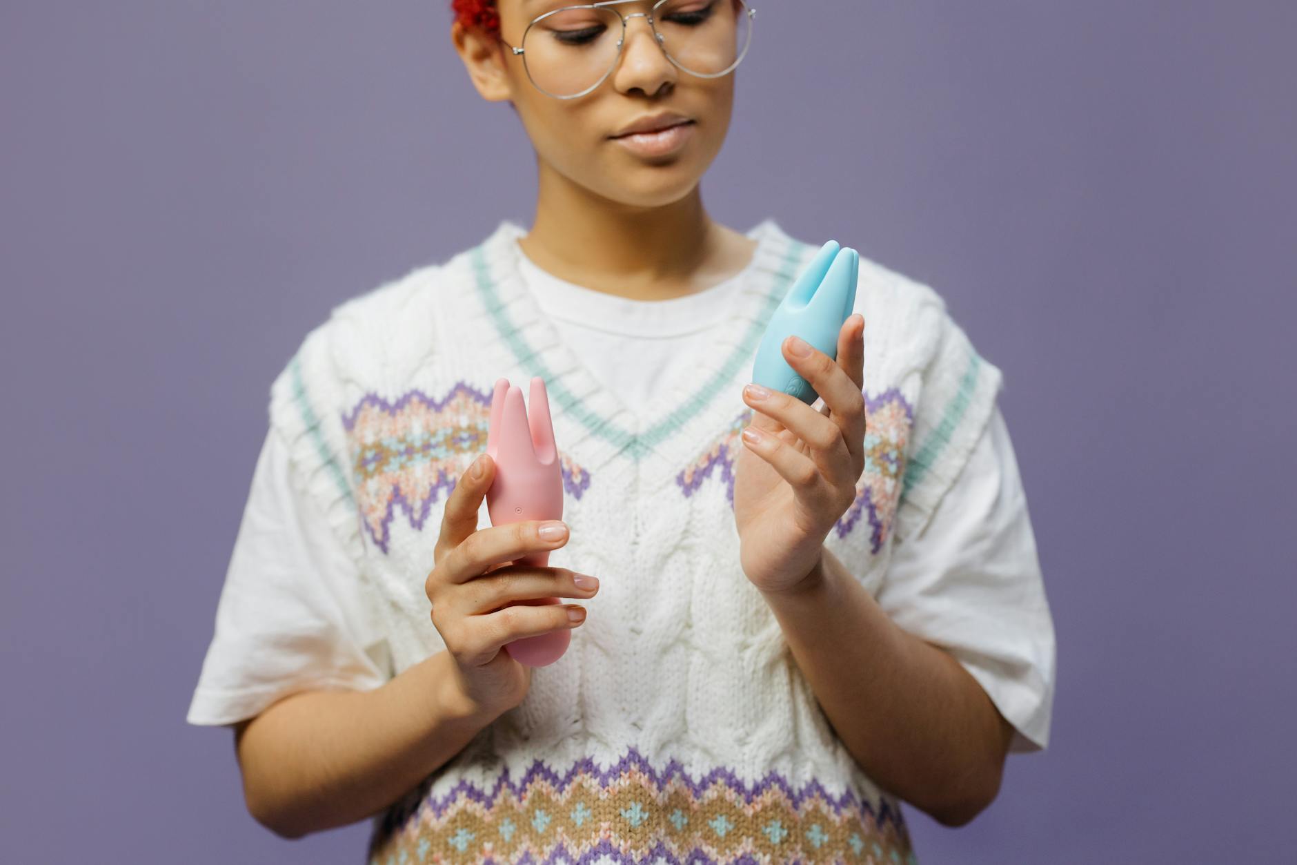 Mujer sosteniendo vibradores de silicona azul y rosa con gesto pensativo