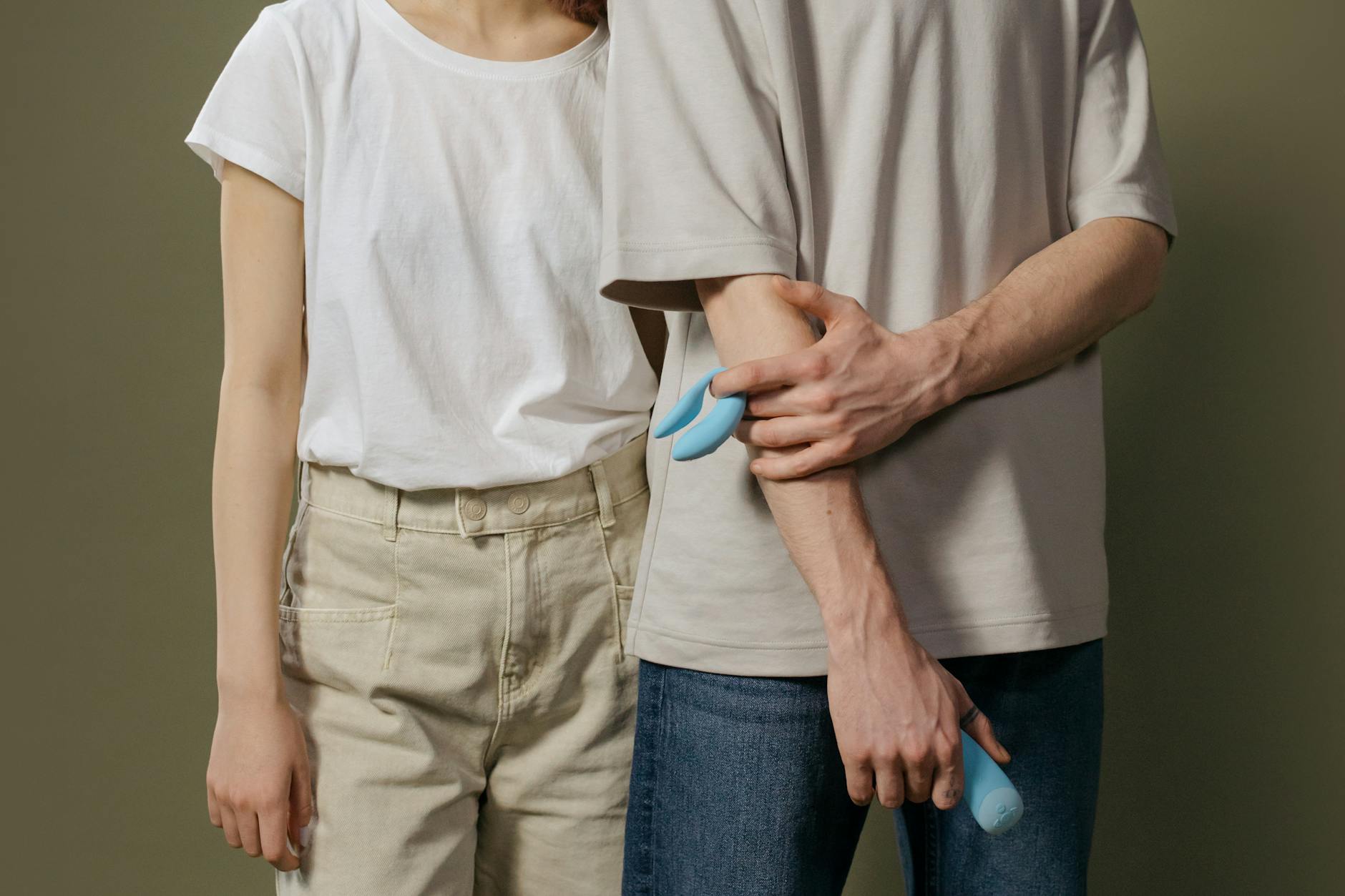 Close-up of a hand holding a blue vibrator above a decorative glass bowl