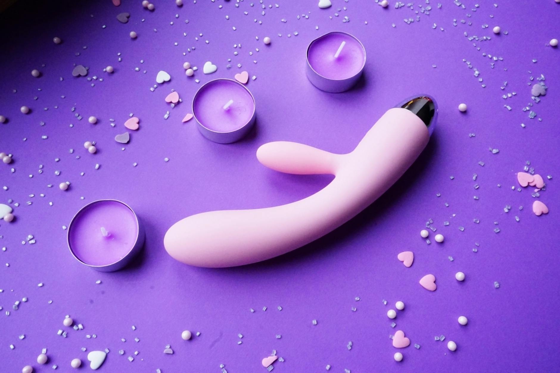 Vibrador de silicona en un fondo de velas y flores para representar intimidad después de los 50